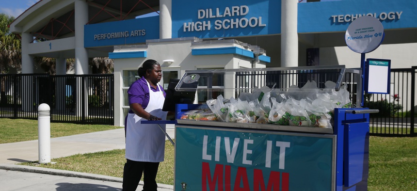 A cafeteria worker pushes a cart full of food to distribute a free lunch to the students and community at Dillard High School amid the coronavirus outbreak and school closings on March 16, 2020, in Fort Lauderdale, Fla.