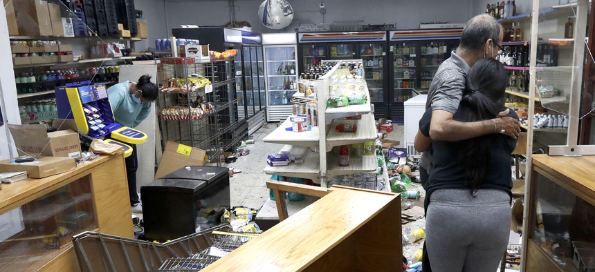 Yogi Dalal hugs his daughter Jigisha as his other daughter Kajal, left, bows her head at the family food and liquor store Monday, Aug. 10, 2020, after the family business was vandalized in Chicago.