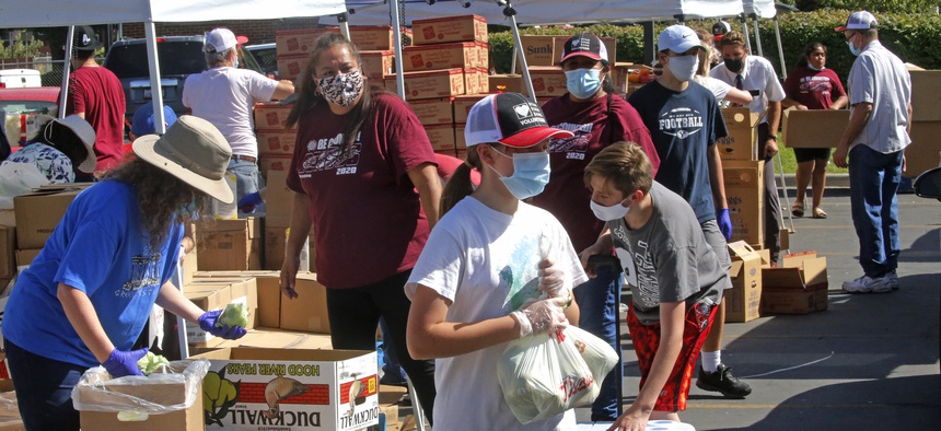 Utah Food Bank volunteers assemble bags of food to be delivered to waiting cars at the food bank's mobile food pantry Wednesday, Aug. 12, 2020, in Salt Lake City, during the coronavirus pandemic.