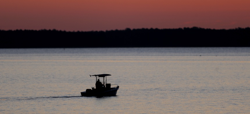 In this May 14, 2020 photo, a small boat chugs along the Honga River near the Chesapeake Bay as the sky lights up at sunrise, in Fishing Creek, Md.