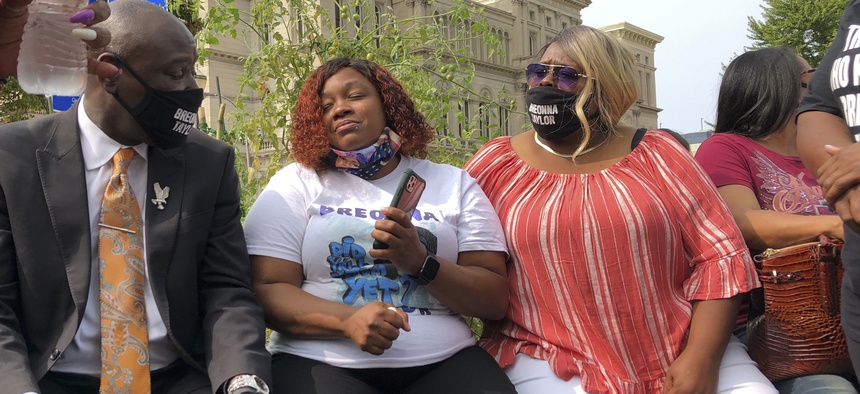 Tamika Palmer, Breonna Taylor's mother, in white beside Attorney Ben Crump, left, speak in Louisville, Ky., after settlement was announced.