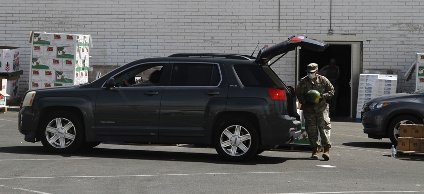 A Texas National Guard soldiers places a watermelon in the back of an SUV at a good bank on May 8, 2020, in Central El Paso, Texas.
