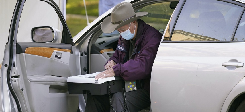 An elderly voter uses the drive-thru option to vote from his car outside Richardson City Hall during early voting Tuesday, Oct. 13, 2020, in Richardson, Texas. (AP Photo/LM Otero)