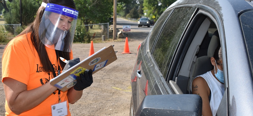 In this Aug. 26, 2020 photo, Lauri Dawn Kindness, left, helps a family participate in the U.S. Census as part of a campaign to increase Native American participation in the count, on the Crow Indian Reservation, in Lodge Grass, Montana.