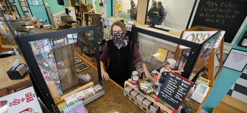 Victoria Leigh Kidd, owner of Hideaway Café, greets customers from behind protective shields in her shop in the Old Town area of Winchester, Va., Wednesday, Oct. 7, 2020.