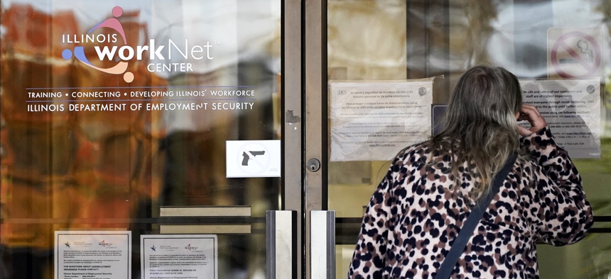 A woman checks information as information signs are displayed at IDES (Illinois Department of Employment Security) WorkNet center in Arlington Heights, Ill., Thursday, Nov. 5, 2020.