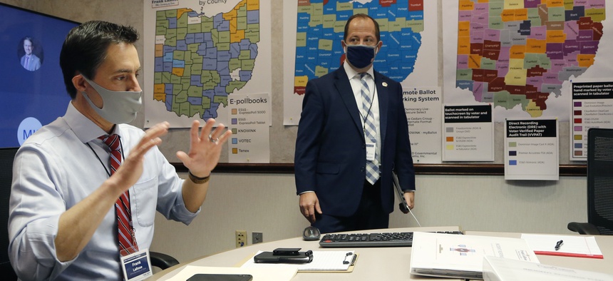 Ohio Secretary of State Frank LaRose, left, interacts with staff members as they follow the election from Ohio's election command center Tuesday, Nov. 3, 2020, in Columbus, Ohio.
