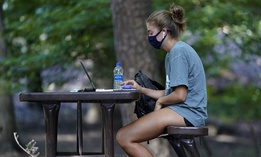 In this Aug. 18, 2020, file photo, a student works outside Ehrighaus dormitory on campus at the University of North Carolina in Chapel Hill, N.C.