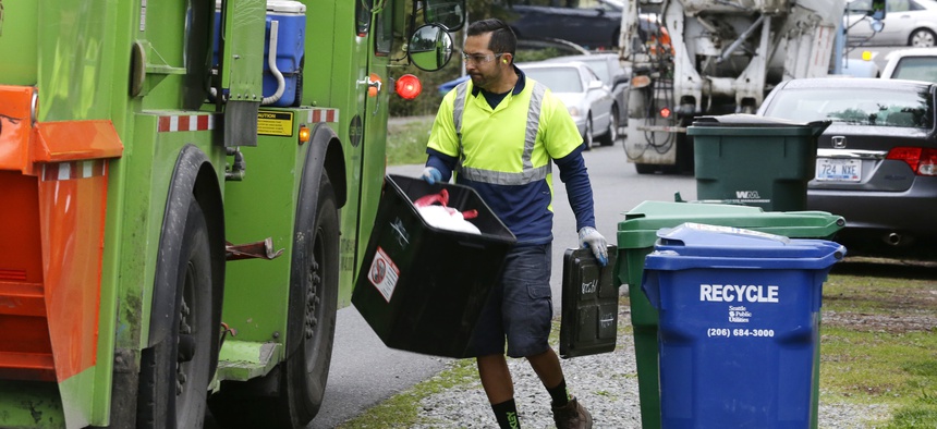 David Morales, a garbage driver with Recology, picks up a garbage container for Seattle Public Utilities, Friday, April 15, 2016, in Seattle.