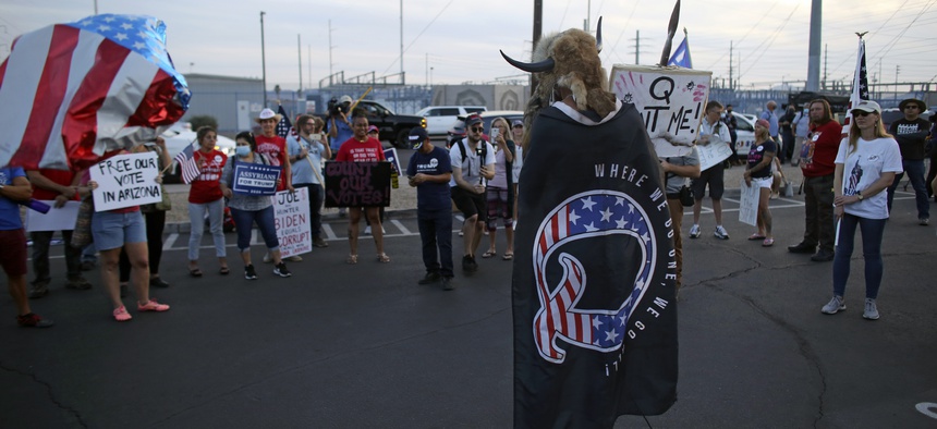 A Qanon believer speaks to a crowd of President Donald Trump supporters outside of the Maricopa County Recorder's Office where votes in the general election are being counted, in Phoenix on Nov. 5, 2020.
