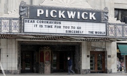 A man wears a mask as he walks in front of the Pickwick Theatre in Park Ridge, Ill., Tuesday, May 5, 2020. The cinema has been closed during the coronavirus pandemic.