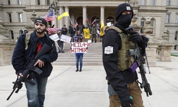 In this April 15, 2020, file photo protesters carry rifles near the steps of the Michigan State Capitol building in Lansing, Mich. 