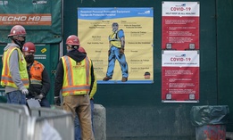 Construction workers wear masks as they stand next to posters with cautions about the spread of COVID-19, Thursday, Dec. 3, 2020.