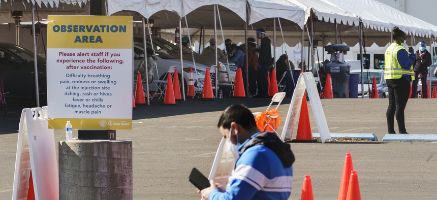 Health workers at an "Observation Area" wait for motorists being inoculated with a COVID-19 vaccine at the mass vaccination site at the parking lot of L.A. County Office of Education headquarters in Downey, Calif., Wednesday, Feb. 3, 2021.