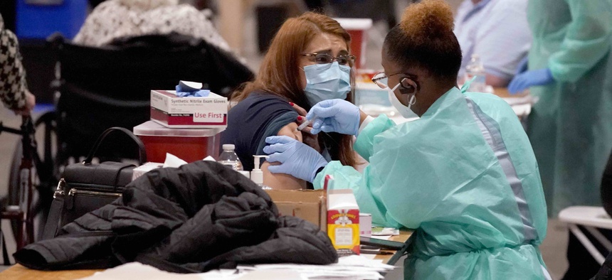 Registered nurse, Adele Prieto, left, receives her second dose of the COVID-19 vaccine from Lesia Turner at the Dallas County mass vaccination site at Fair Park Wednesday, Jan. 20, 2021, in Dallas.