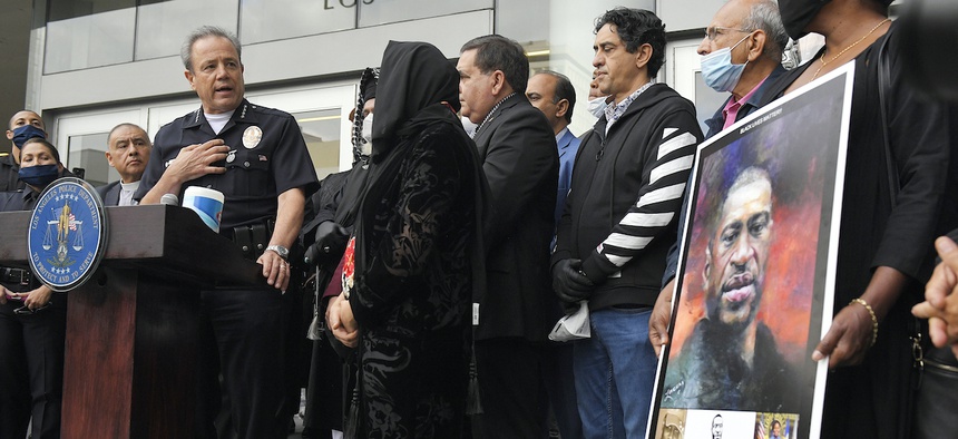 In this June 5, 2020, file photo, Los Angeles Police Chief Michel Moore, left, speaks as someone holds up a portrait of George Floyd during a vigil with professional associations and the interfaith community at Los Angeles Police Department headquarters.