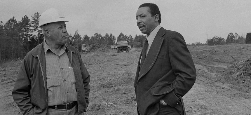 Former civil rights lawyer-activist Floyd McKissick, right, talks to grade foreman A.T. Ayscue, in the empty fields where the future "Soul City" will be built in Warren County, N.C., June 20, 1974.