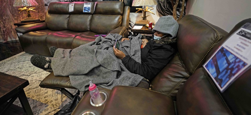 Natalie Harrell holds her sleeping daughter, Natasha Tripeaux while sitting in a recliner at a Gallery Furniture store after the owner opened his business as a shelter for those without power at homes Tuesday, Feb. 16, 2021, in Houston.