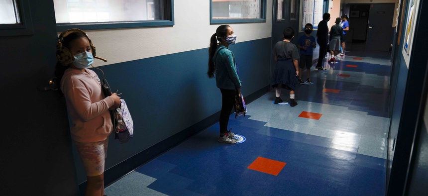 In this Aug. 26, 2020, file photo, Los Angeles Unified School District students stand in a hallway socially distance during a lunch break at Boys & Girls Club of Hollywood in Los Angeles.