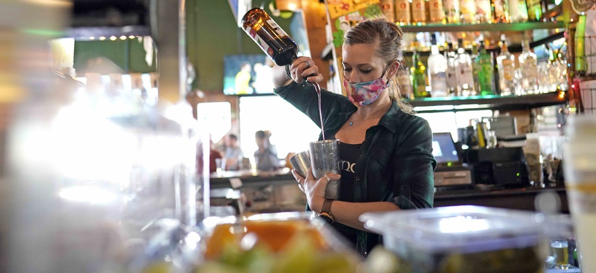 Bartender Alyssa Dooley makes a cocktail at Mo's Irish Pub, Tuesday, March 2, 2021, in Houston. Texas Gov. Greg Abbott announced Tuesday that he is lifting business capacity limits and the state's mask mandate starting next week.