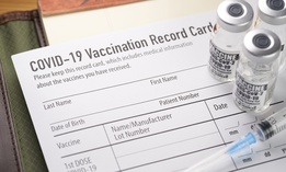Covid-19 vaccination record card with vials and syringe.